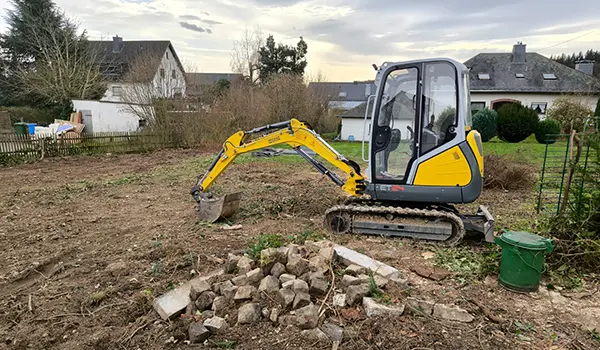 Bagger auf einem Baugrundstück und ein Haufen ausgehobener Steine