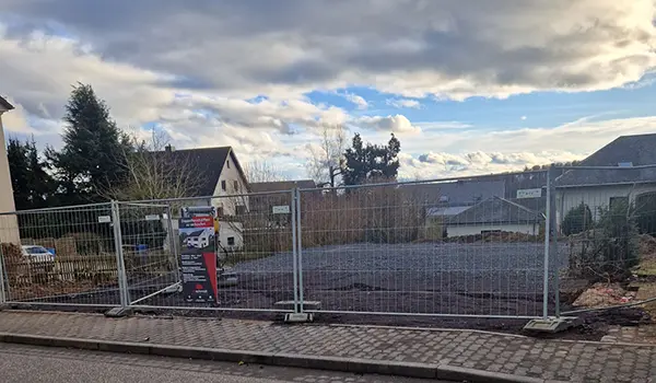 Baugrundstück mit Bauzaun in einem Wohngebiet, geebneter Boden