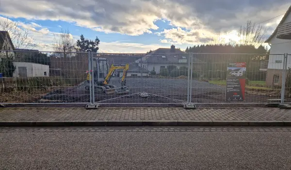 Baugrundstück mit Bauzaun von außen, geebneter Boden